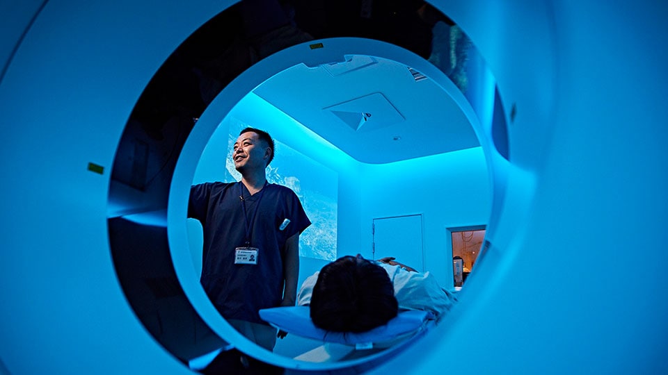 Foto di un medico che imposta una scansione sul gantry dello scanner TC, con il paziente sul lettino paziente del sistema TC