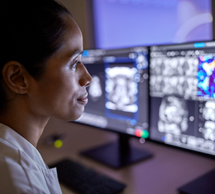 Medico di fronte a più monitor che mostra scansioni RM