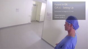 Campo visivo di una persona che indossa i Google Glass – Un medico percorre un corridoio visualizzando i parametri vitali del paziente nell'angolo in alto a destra del campo visivo.