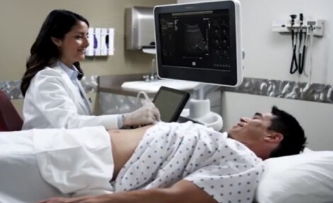 un uomo sdraiato su un letto con un medico sullo sfondo