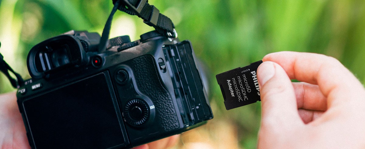 Una persona che tiene una fotocamera in una mano e una scheda di memoria nell'altra, pronta per memorizzare foto