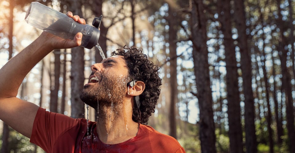 Atleta che versa acqua sulle cuffie open ear impermeabili