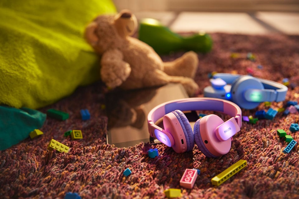 Cuffie per bambini blu e rosa per terra con giocattoli