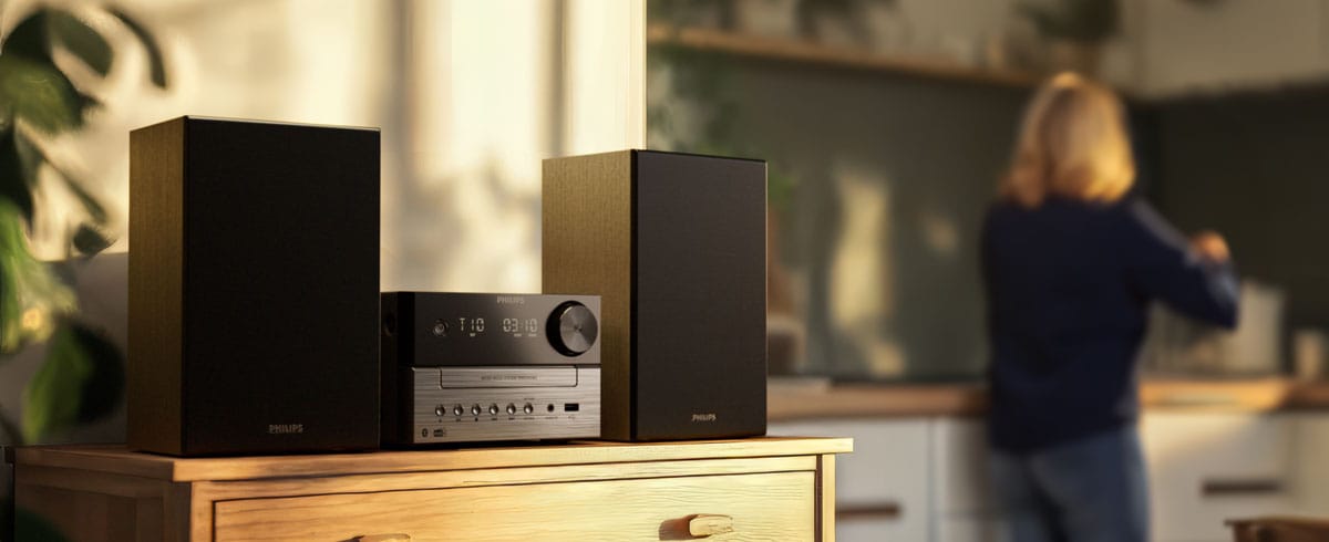 Donna che ascolta musica in cucina con un sistema musicale Philips
