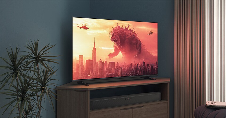 Una TV Philips su un supporto angolare mostra un film di Godzilla