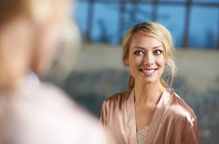 una donna in vestaglia sorride, mostrando i suoi denti bianco perla.