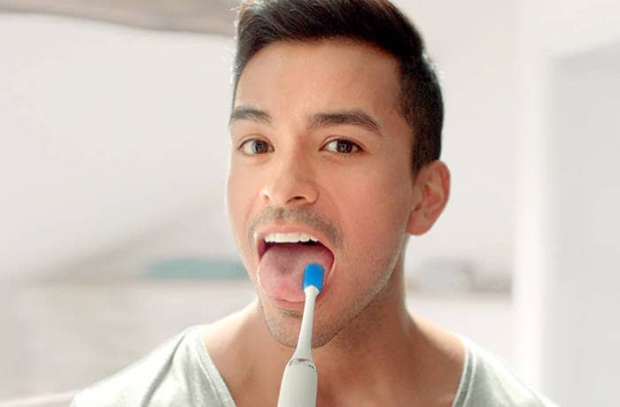 : Primo piano di un uomo che pulisce la lingua usando uno speciale spazzolino per lingua Philips.