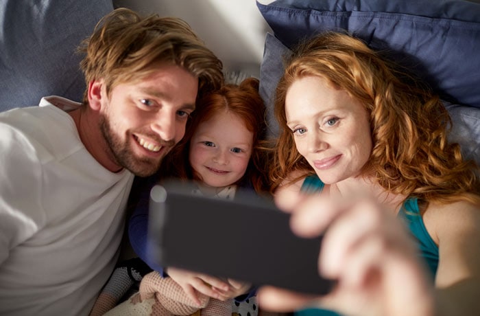 una donna si fa un selfie con il marito e la figlia piccola.