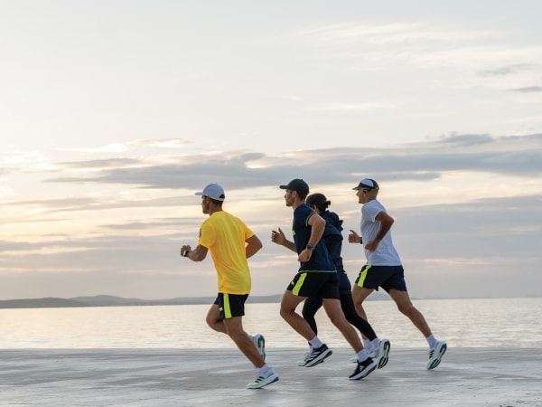 Quattro partecipanti alla corsa corrono insieme sulla spiaggia.