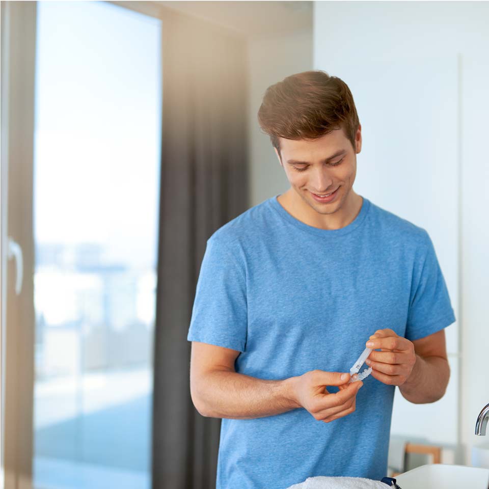 Un uomo applica gel sbiancante su un vassoio personalizzato