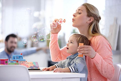 Bambino che gioca con la mamma con le bolle di sapone.