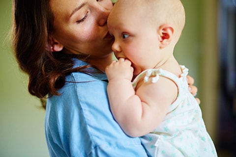 Mamma che tiene in braccio il bebè e aspira il suo profumo