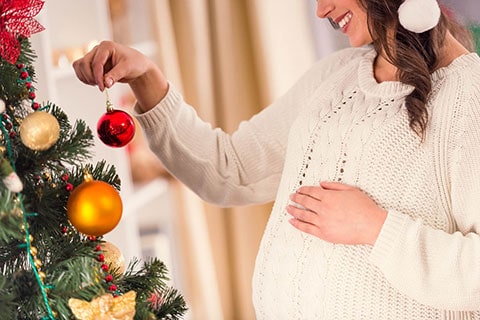 Mamma in gravidanza vicino ad un albero di Natale addobbato