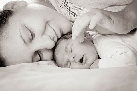 Mamma e neonato sdraiati insieme a letto
