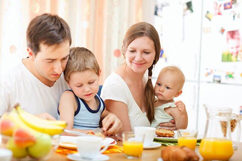 Famiglia con bambini che fa una ricca colazione al mattino