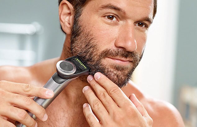 Primo piano di un uomo a petto nudo che si rade la barba utilizzando un rasoio elettrico.