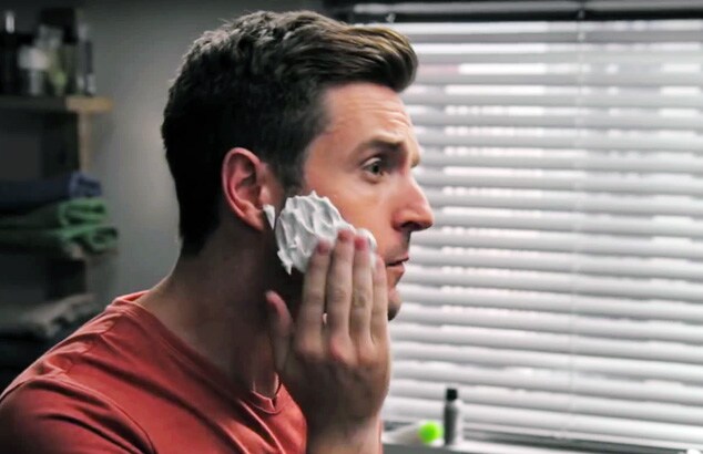 uomo in un bagno che si applica la schiuma da barba sul viso.