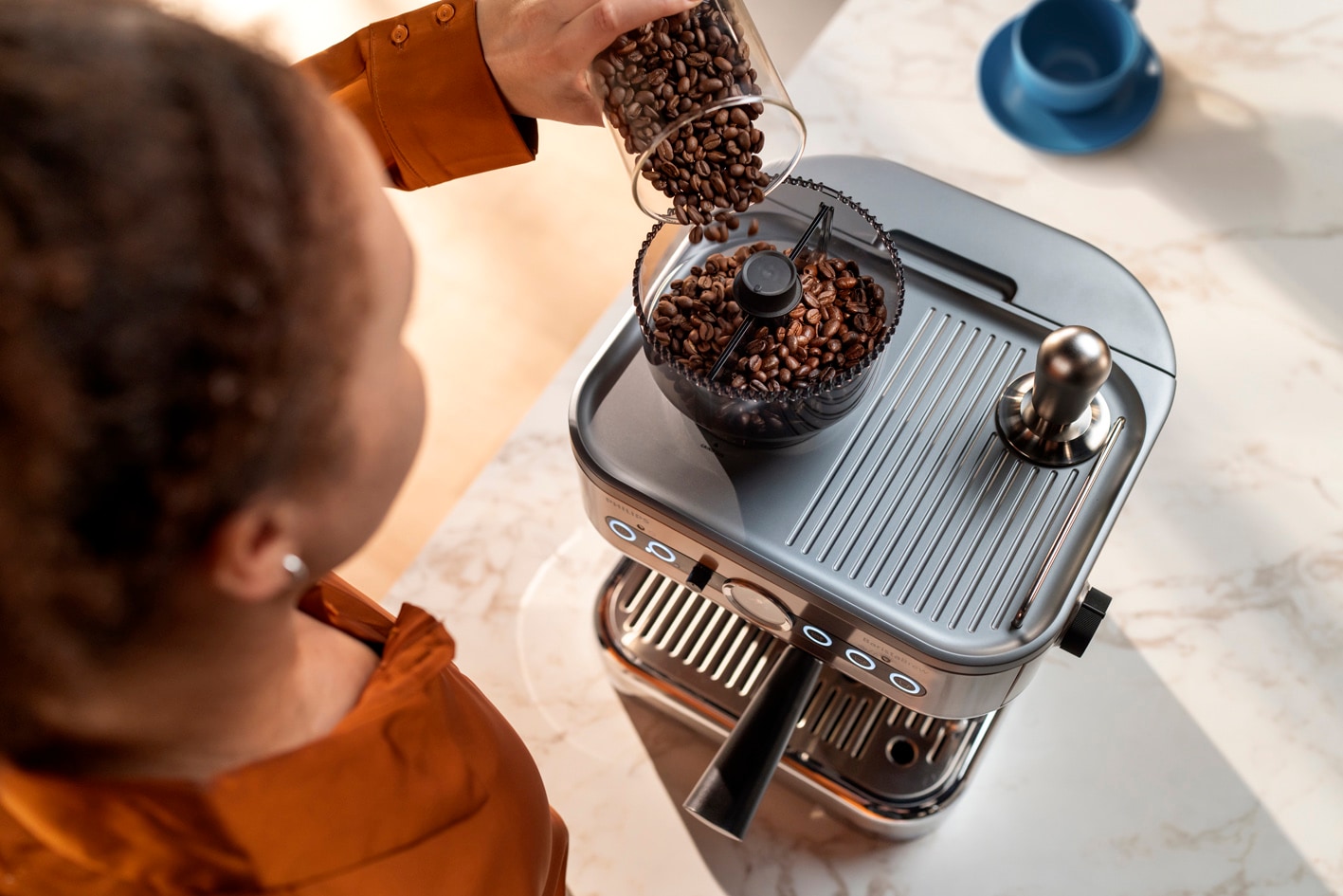 Una giovane donna che versa il caffè in grani nell'apposito recipiente di Philips Barista Brew
