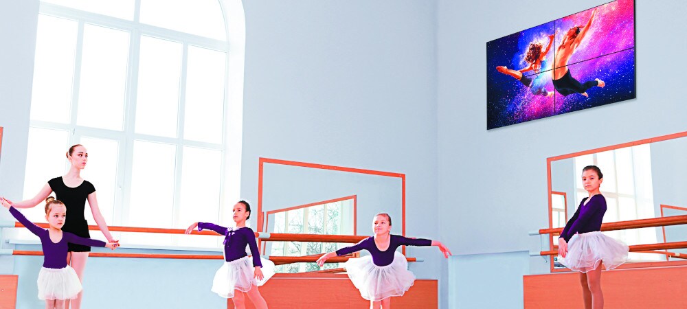 Display digitale Signage a parete. Dei bambini imparano la danza classica in una stanza