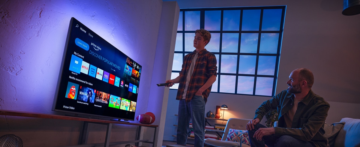 Un uomo che sceglie un'app dallo Smart TV Philips